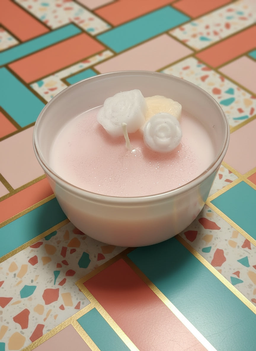 Pink candle with decorative elements in a container on a wooden surface
